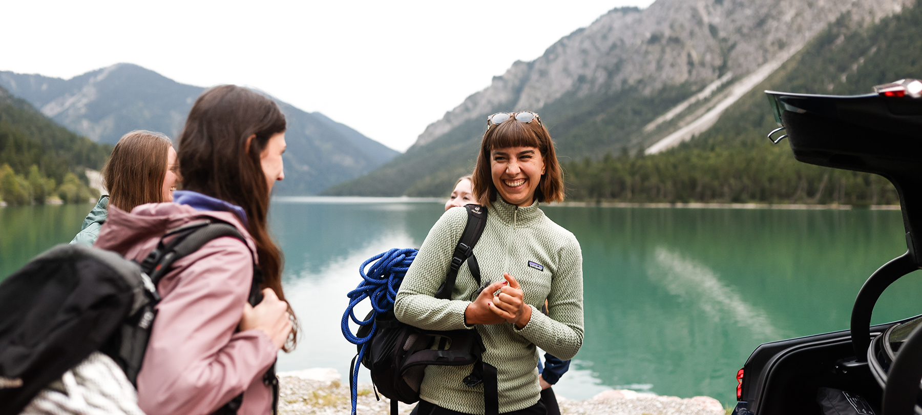 A female employee at the BMW Group enjoying her freetime with colleagues at a lake and mountains in the background.