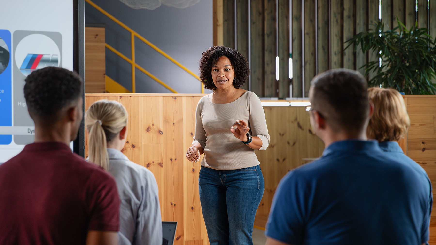 A female Employee of the BMW Group is presenting to a Group of People.