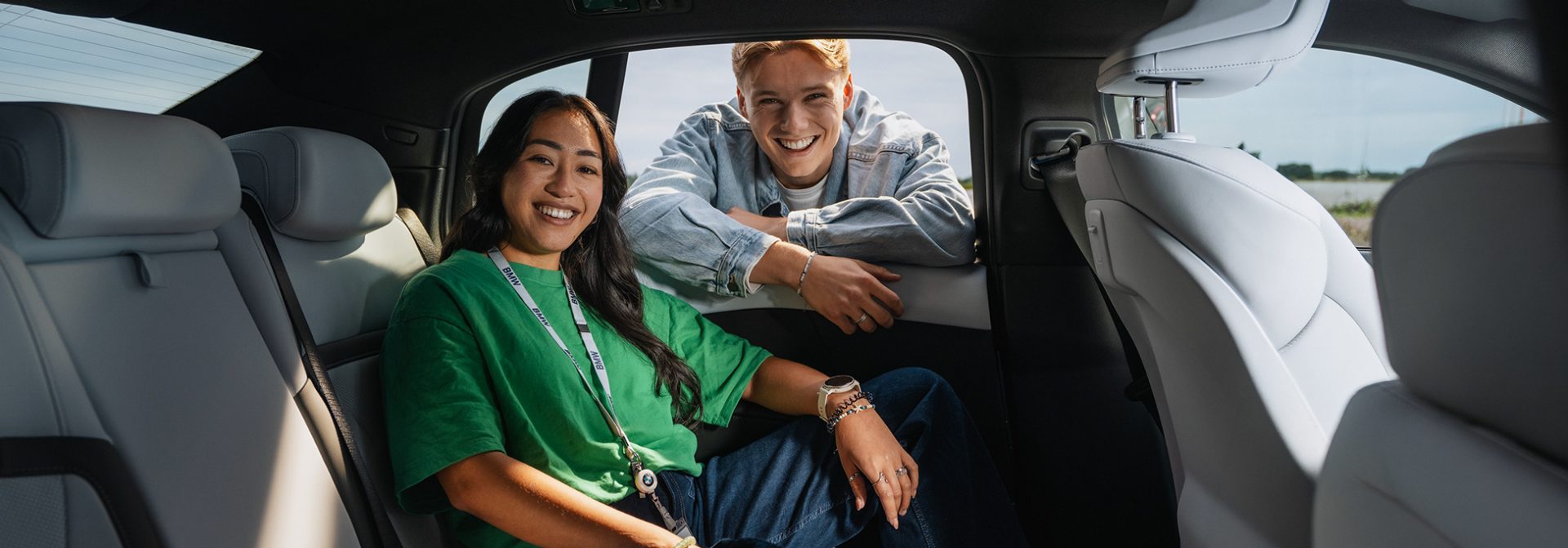 A female student in the back seat of a BMW i3 and a male student looking out the window