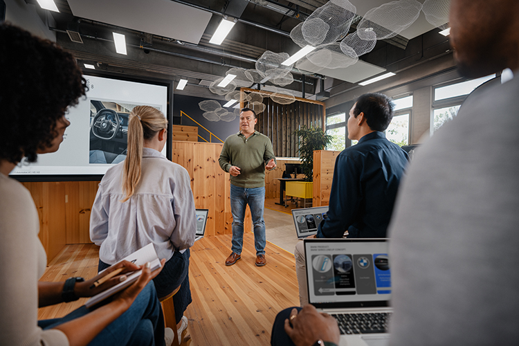 A Employee of the BMW Group is presenting to a Group of People.
