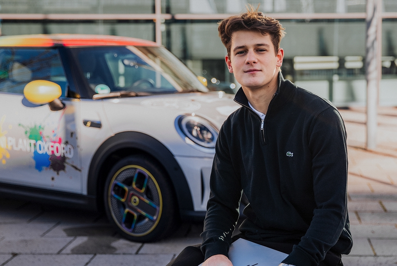 Portrait of a Dual Student in Sustainability & Environmental Management sitting in front of a MINI.