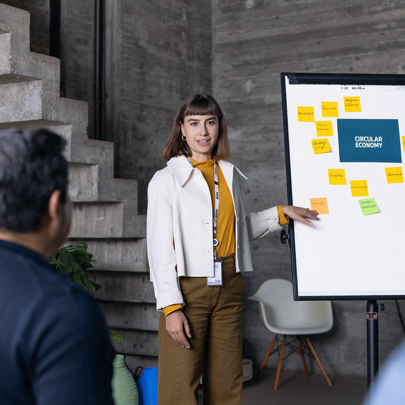 The female employee in sustainability is presenting her bulletpoints about circular economy infront of a group of colleagues.