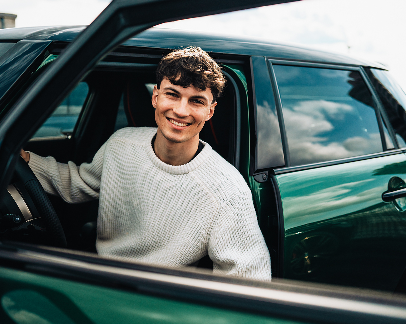 Anton, a work-study student, is sitting in a green MINI Cooper