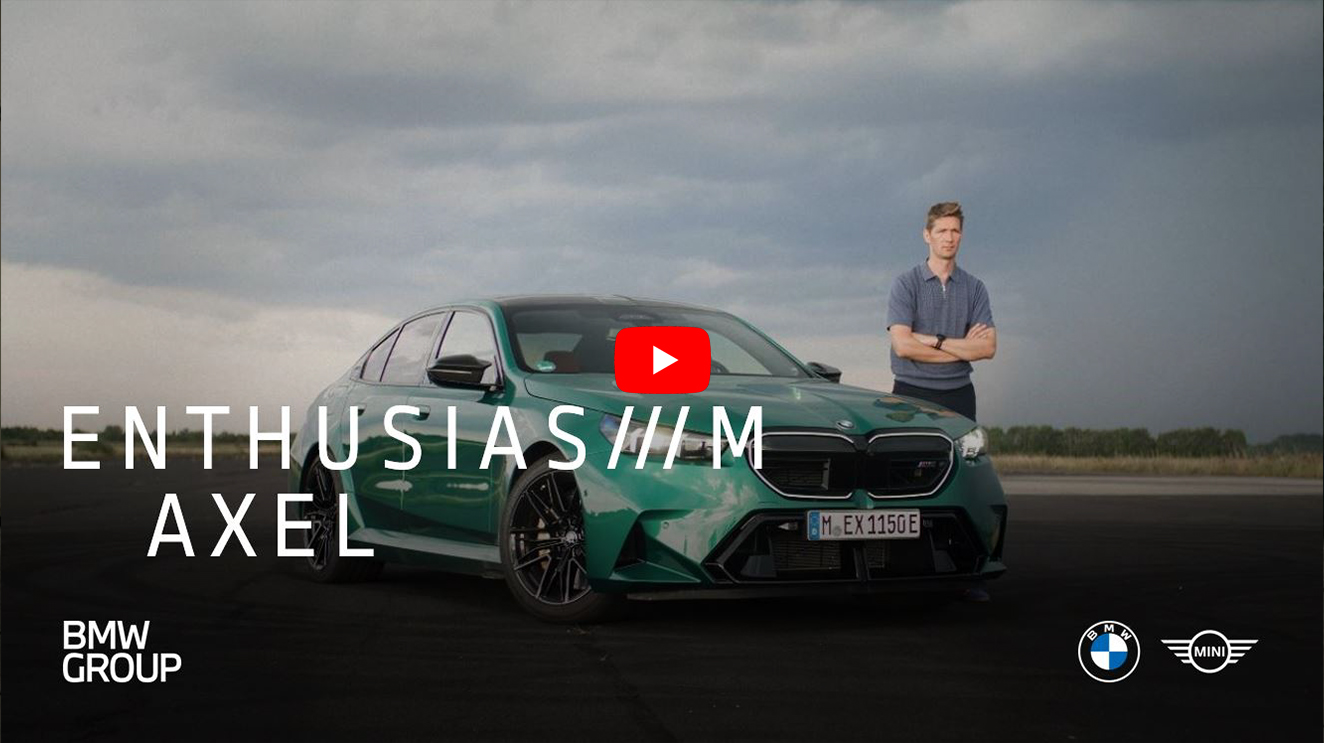 Axel stands with his arms folded next to a BMW M5