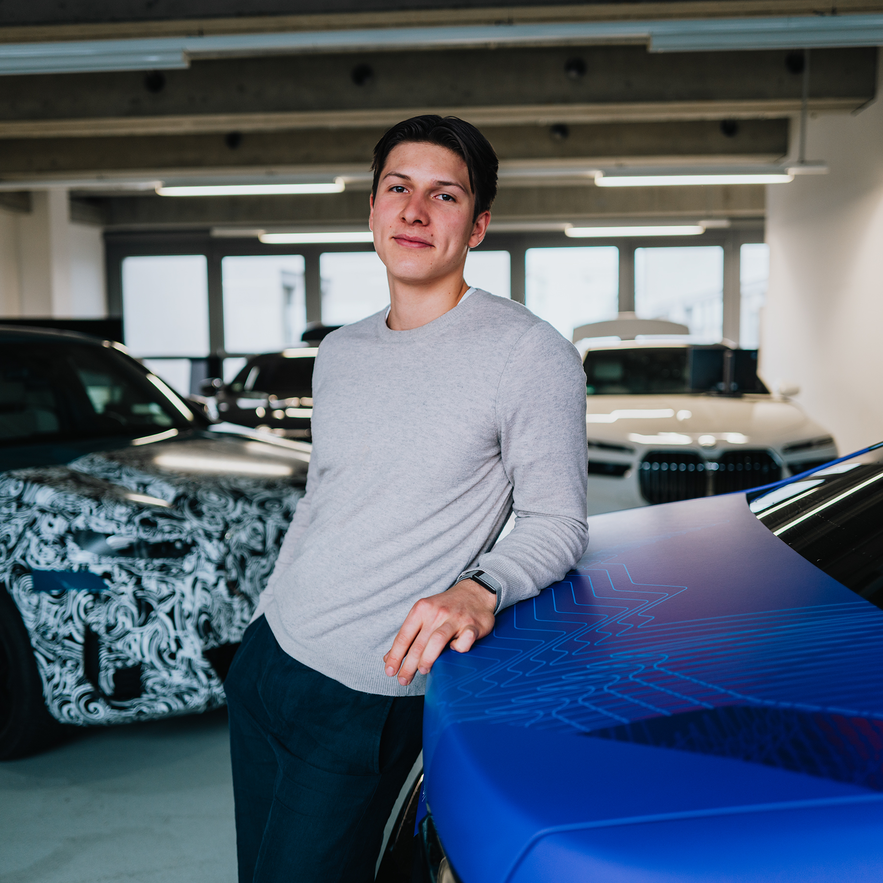 Arne is leaning against a BMW i7 in a test environment.