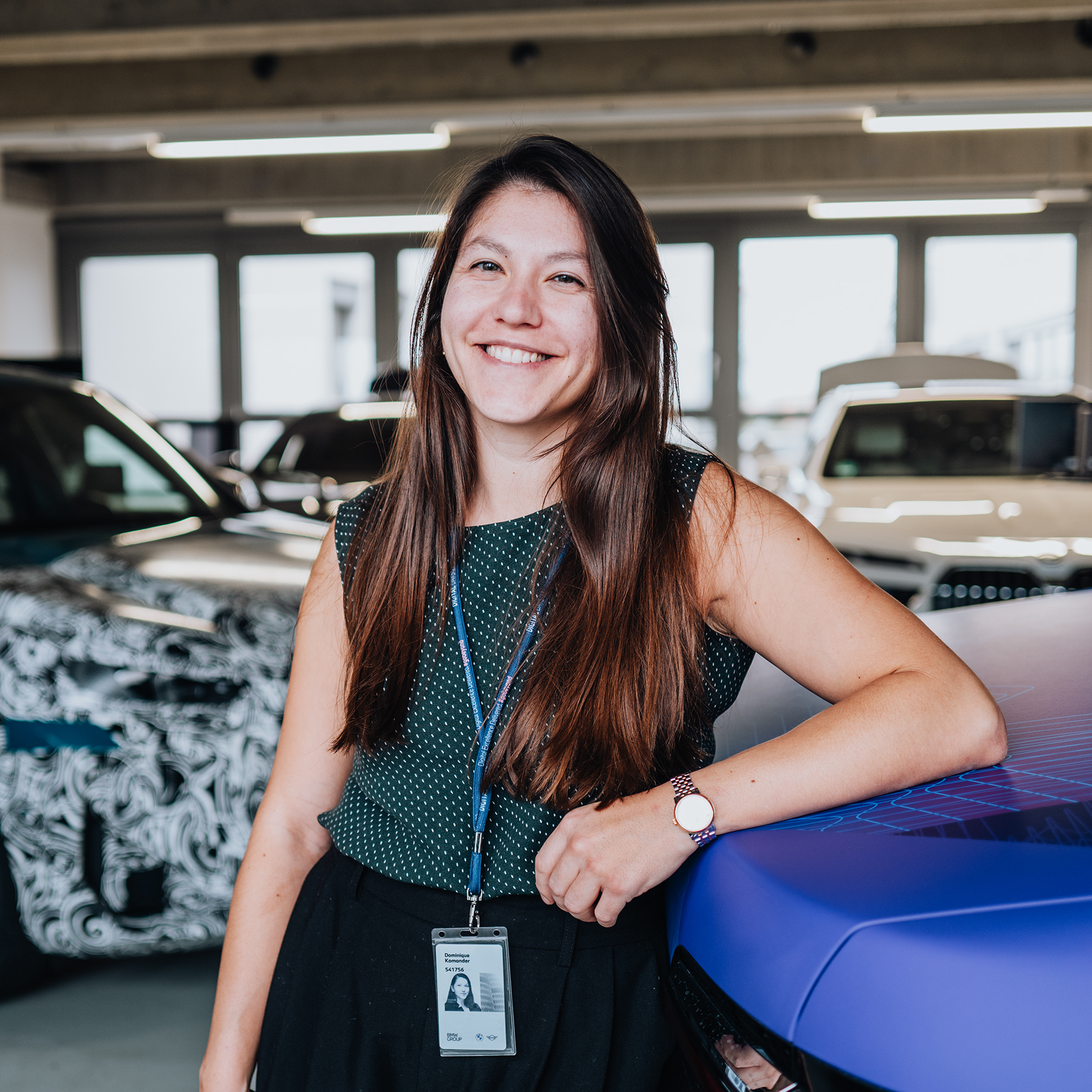 Dominique is leaning against the rear of the BMW i7.