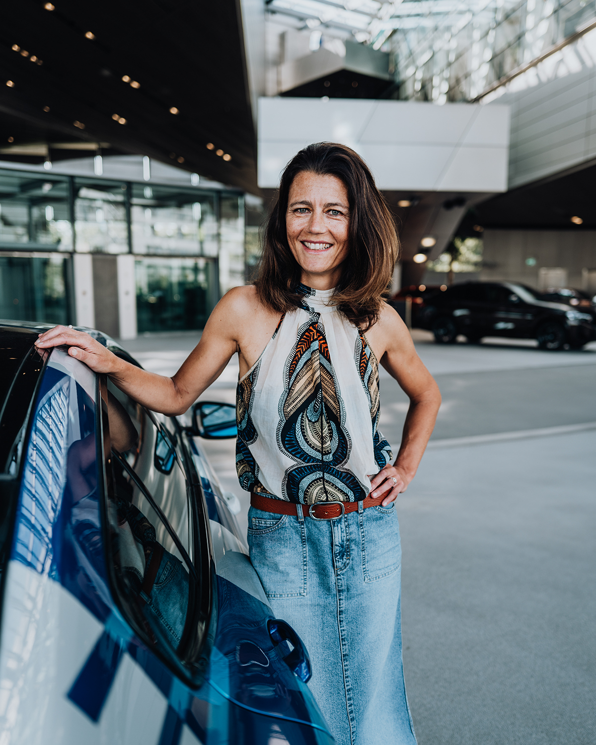 The other woman of the leadership duo is leaning against the BMW M8.