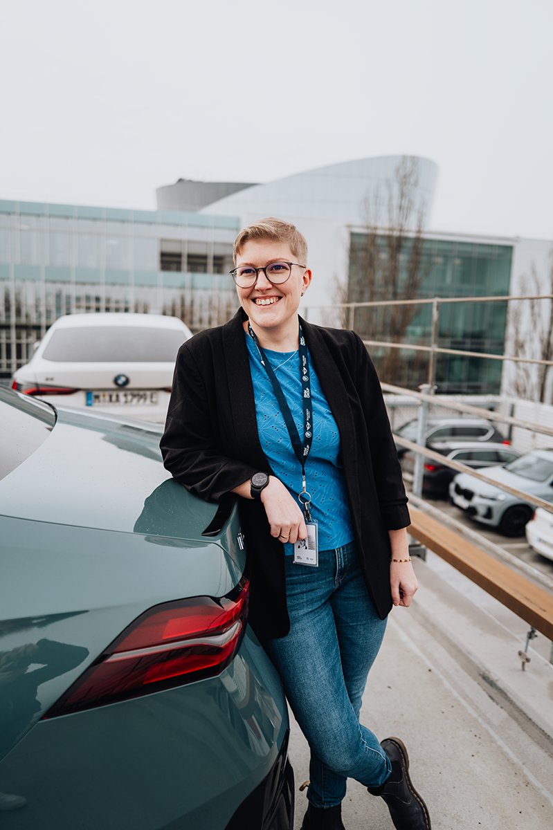PhD student Erla leans against the trunk of a BMW i5.