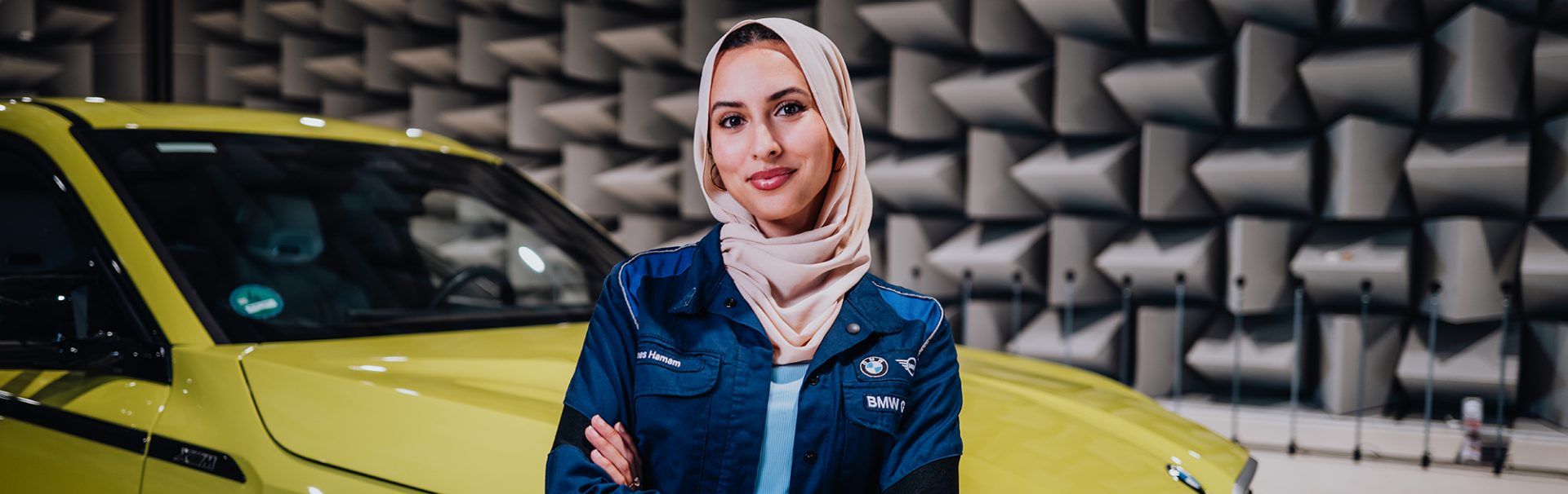 Ines in front of a BMW XM with crossed arms.