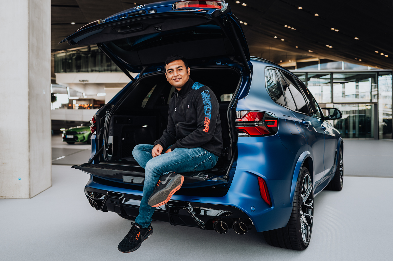 Trainee Kartikey sitting in the trunk of a BMW X5M at BMW Welt Munich