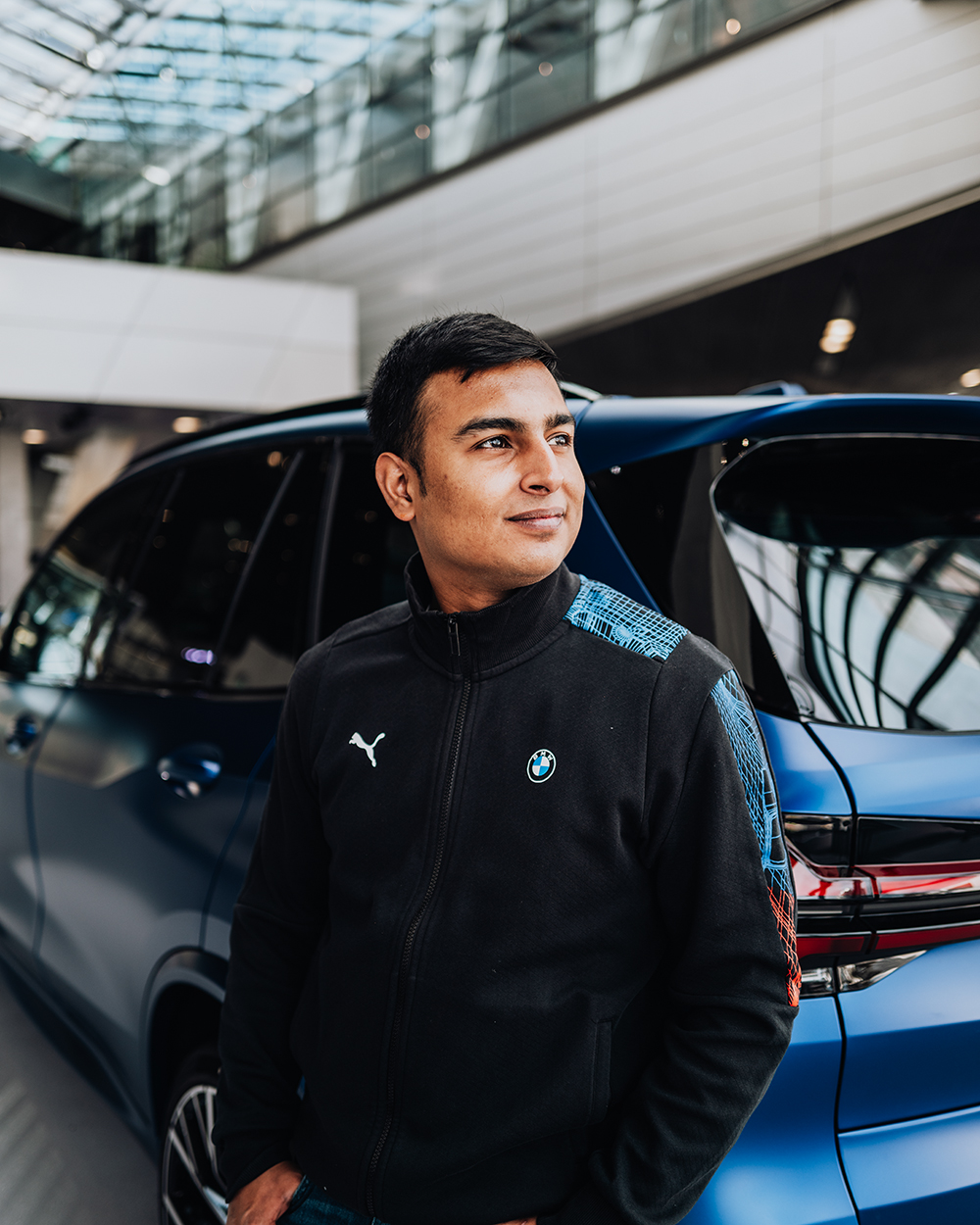 Trainee Kartikey standing in front of a blue BMW X5M at BMW Welt Munich