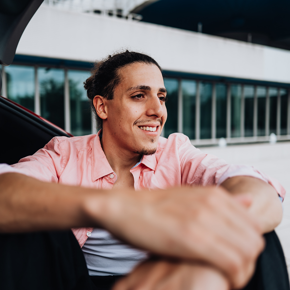The BMW Group employee is sitting inside the trunk of a BMW i5 and smiles.