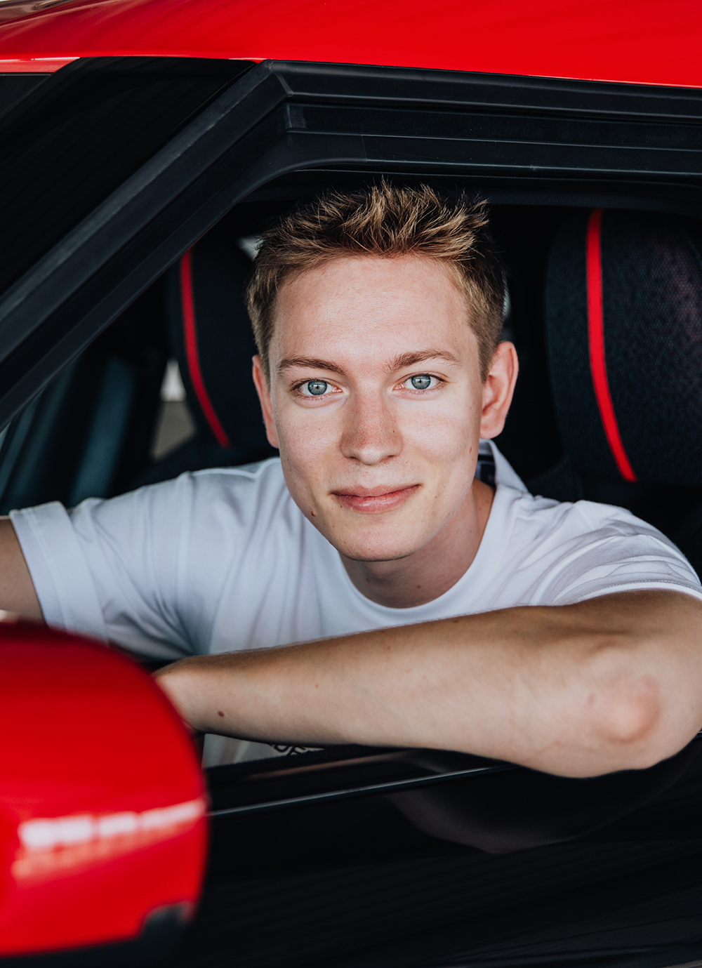 Student sitting in the Driver's seat of a MINI Countryman leaning ot of the window to smile at the camera.