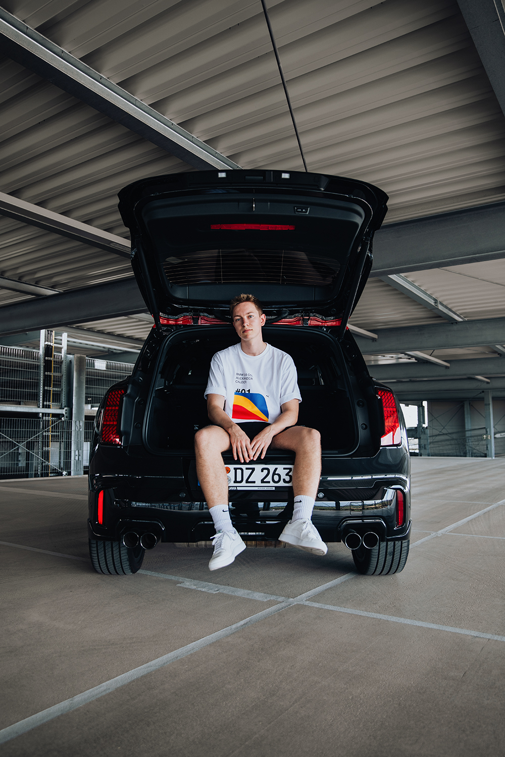 Student sitting in the trunk of the MINI Countryman with his legs hanging out.