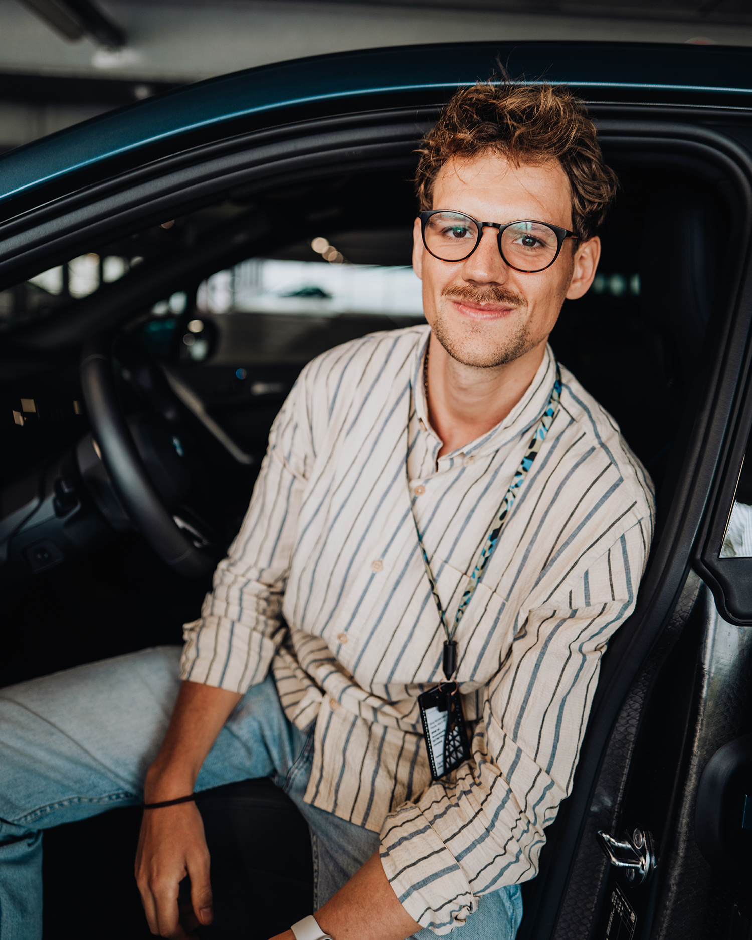 PhD student Phillip sits in the drivers seat of the BMW iX.
