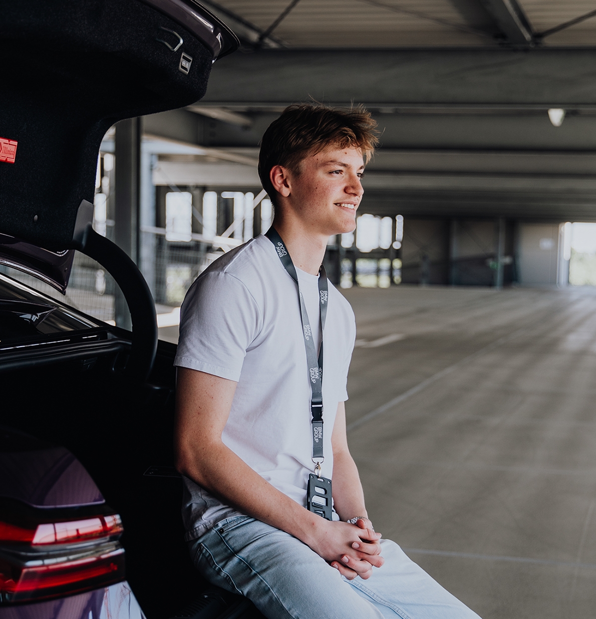 Apprentice Tobias sits on the trunk loading ramp of a BMW M5