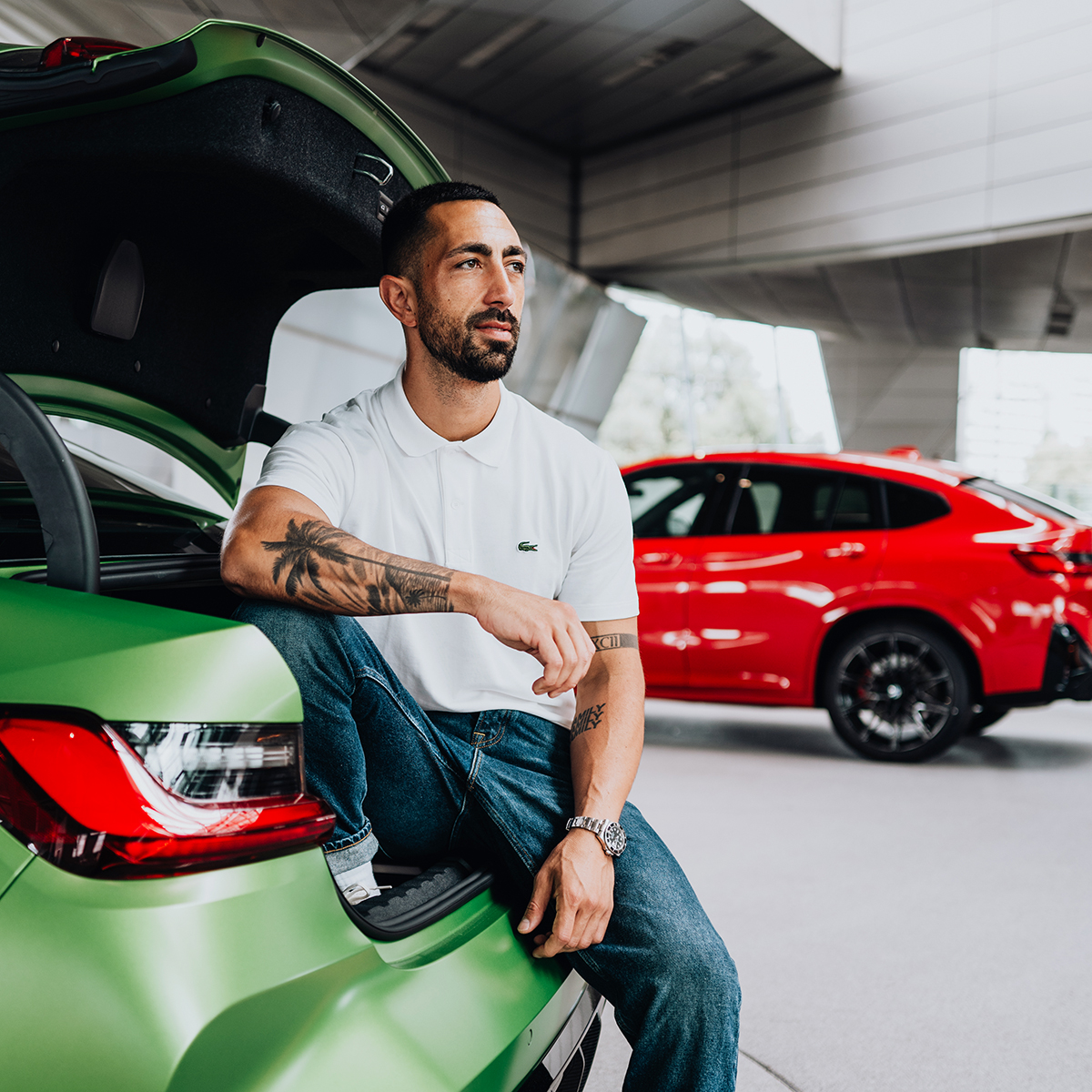 BMW Group employee sitting in the Trunk of a green BMW M3.