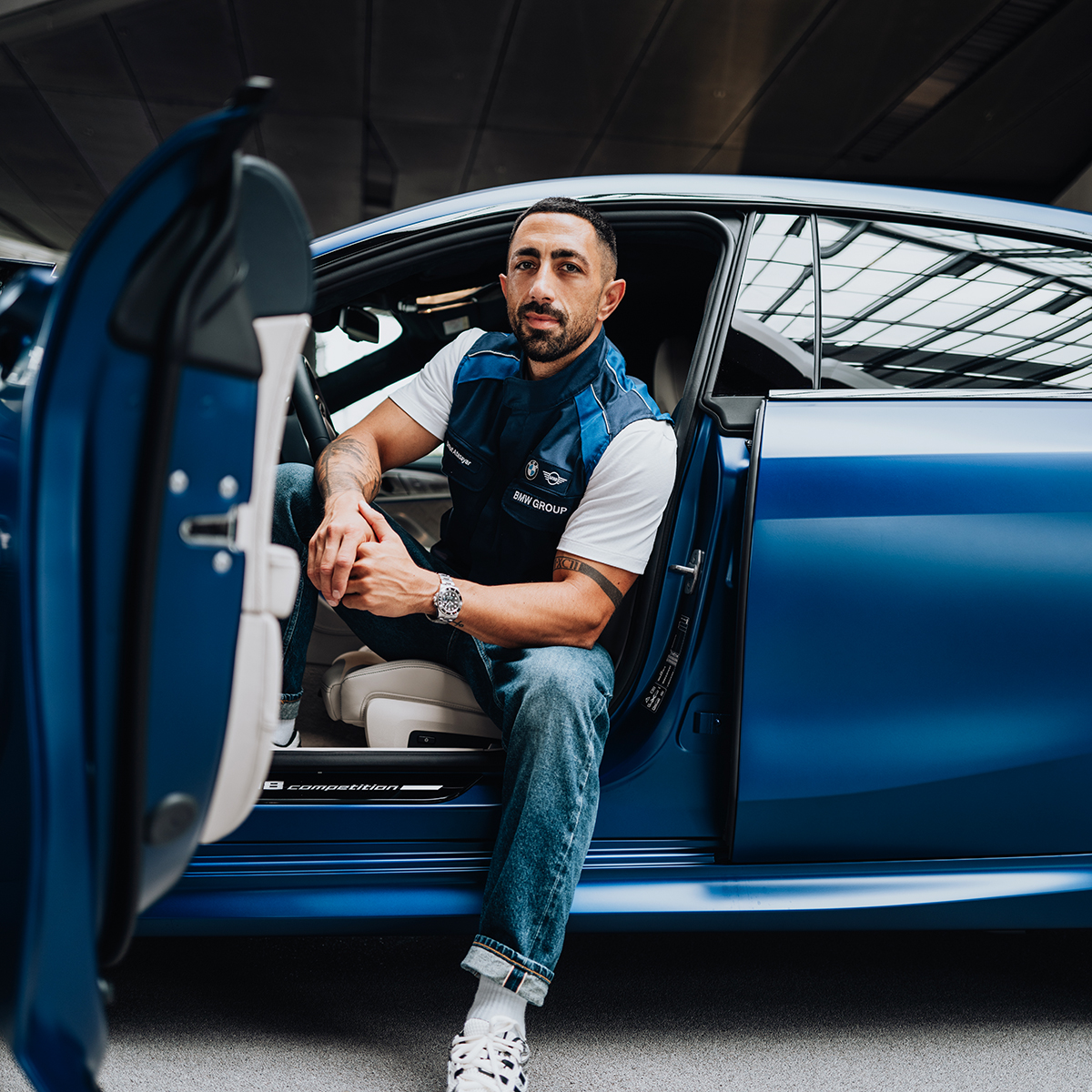 BMW Group employee leaning out of the driver's seat of a BMW M8.