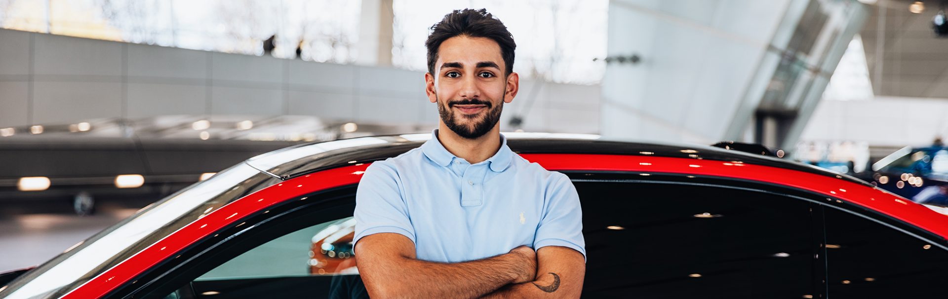 Yasar in front of a BMW M5 with crossed arms.