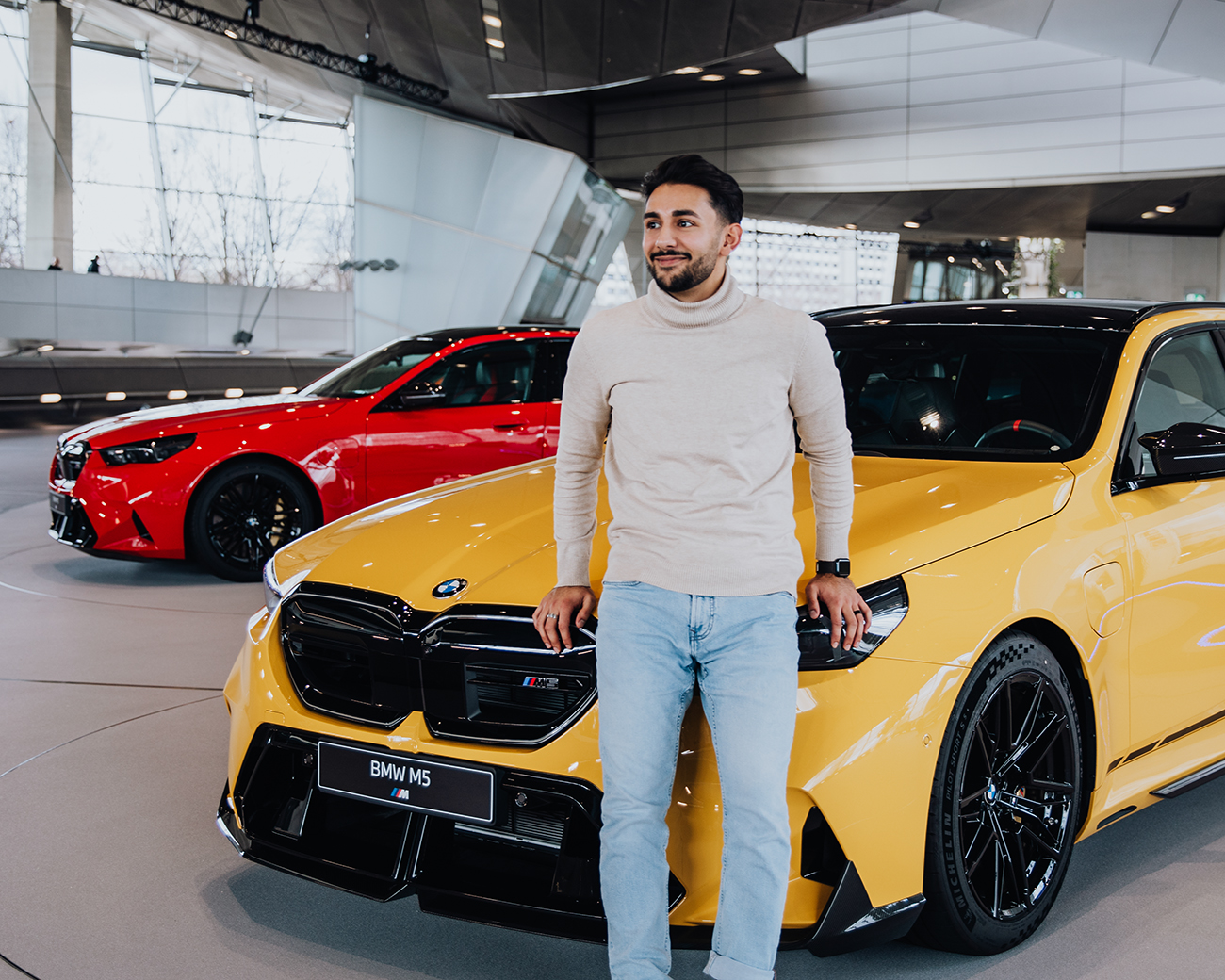 BMW employee Yasar leaning against a yellow BMW M5