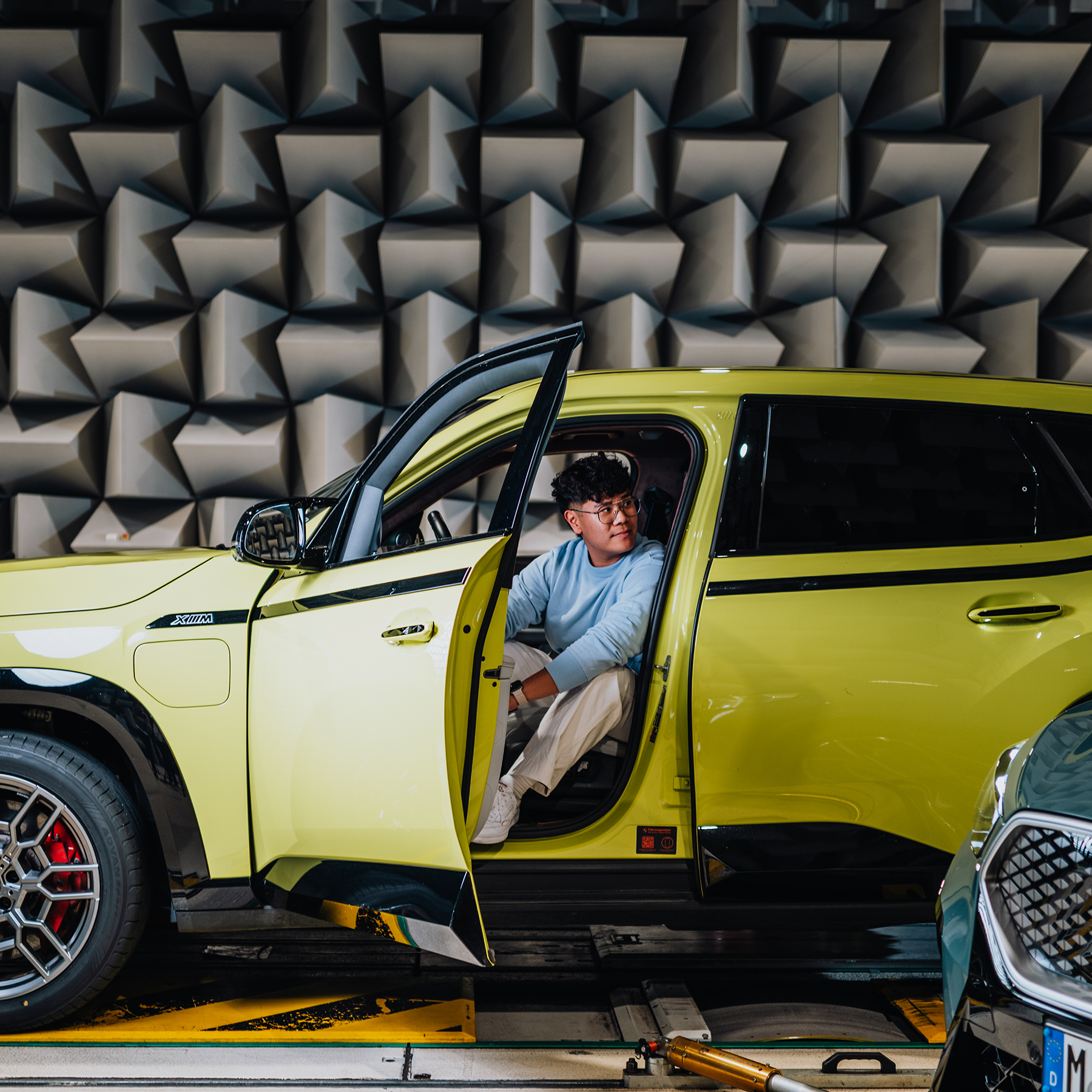 Yian on the drivers seat of a yellow BMW XM.