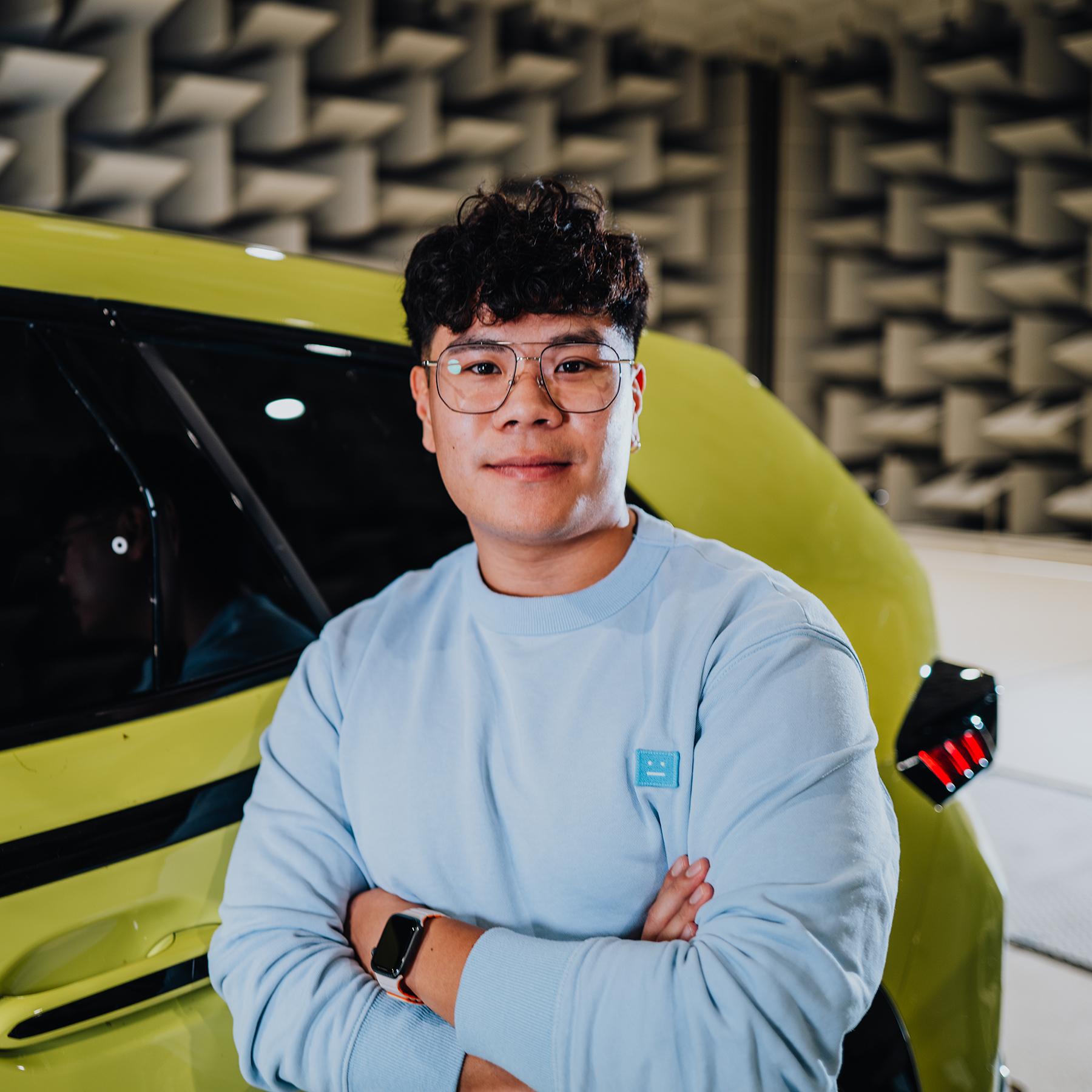 Yian looks into the camera, standing in front of the rear end of a BMW XM.