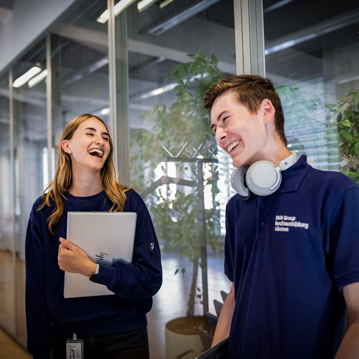 Two smiling apprentices are chatting in a BMW Group office.