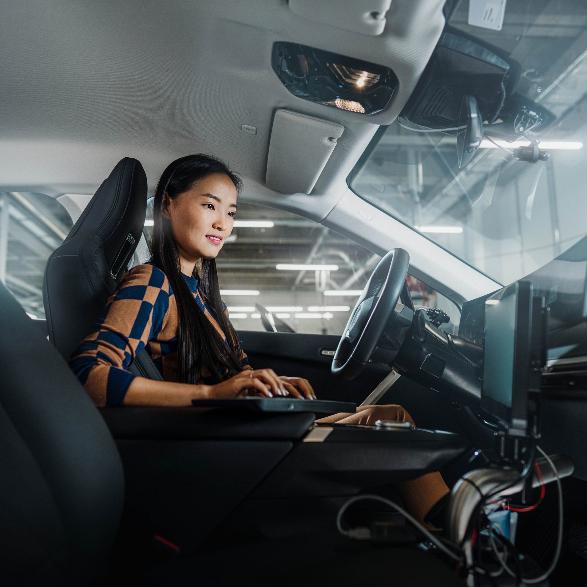 The image shows a BMW Group employee analysing data in a vehicle.