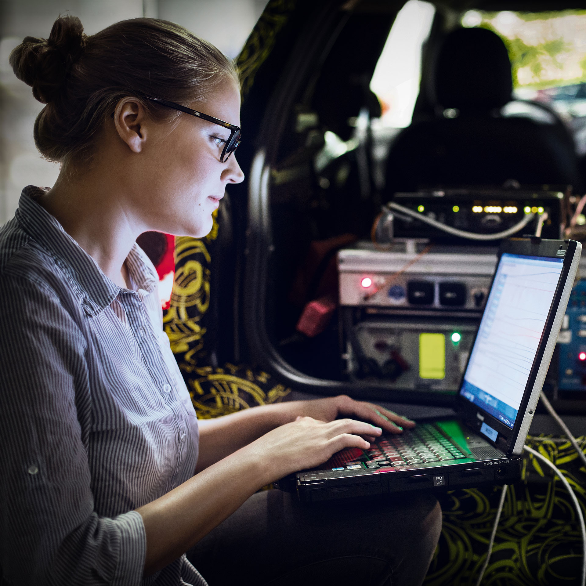 The image shows a BMW employee analying vehicle data.