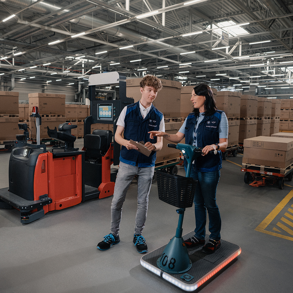The image shows two logistics workers in a warehouse.