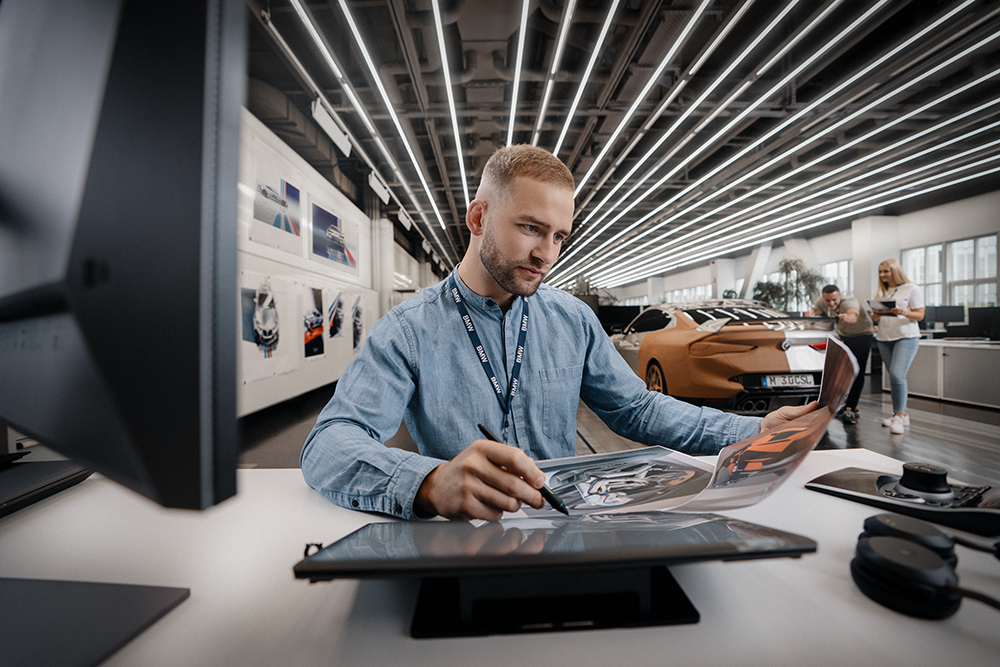 An automotive designer sketching a new car concept in a contemporary design studio.