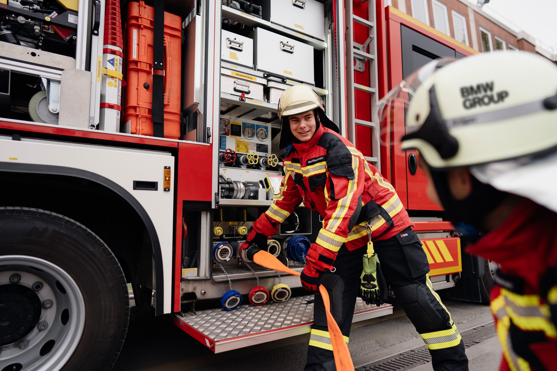 BMW fire brigade apprentices in action with a BMW i3 Fire Brigade Car next to them.