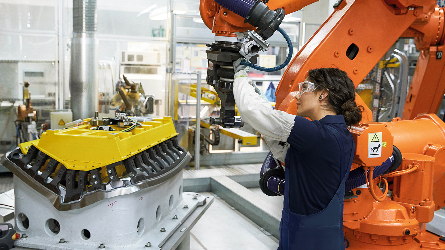 Female Employee in Plant operation working on a robotic arm.