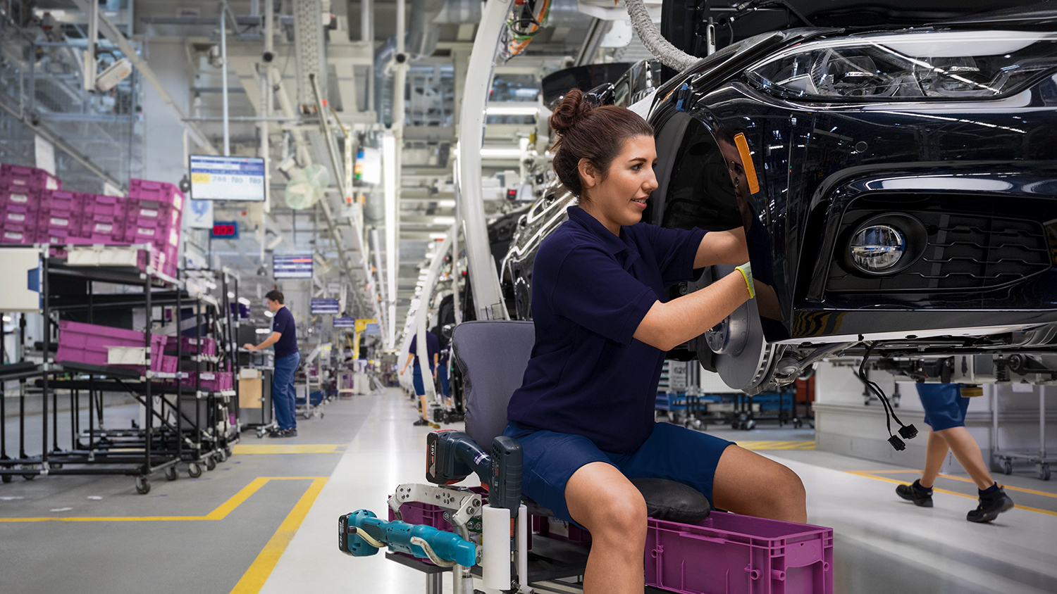 Female employee in Montage working on fixing car parts to a car body.