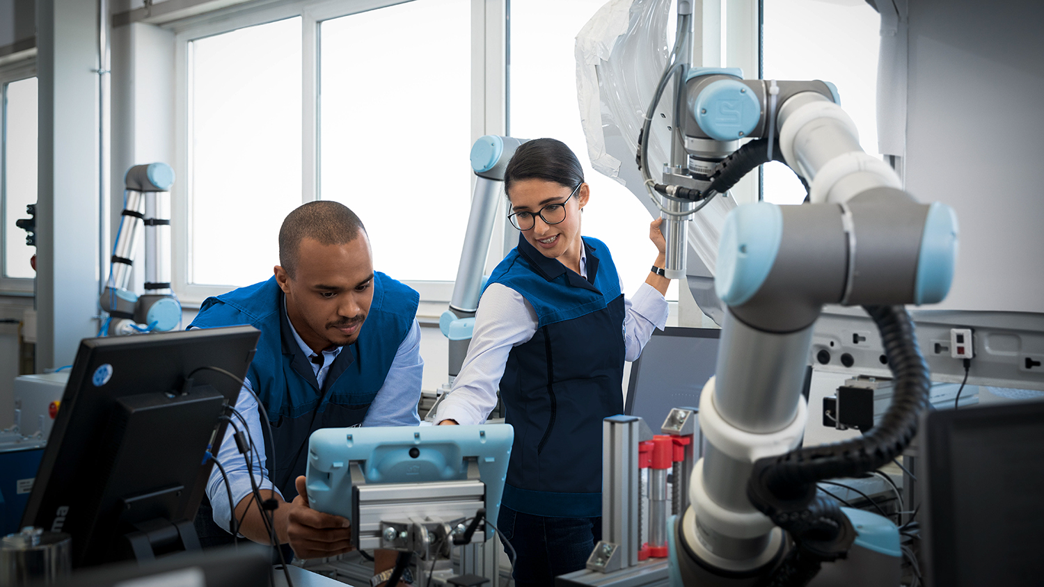 Two employees in Industry 4.0 working on a robotic arm.