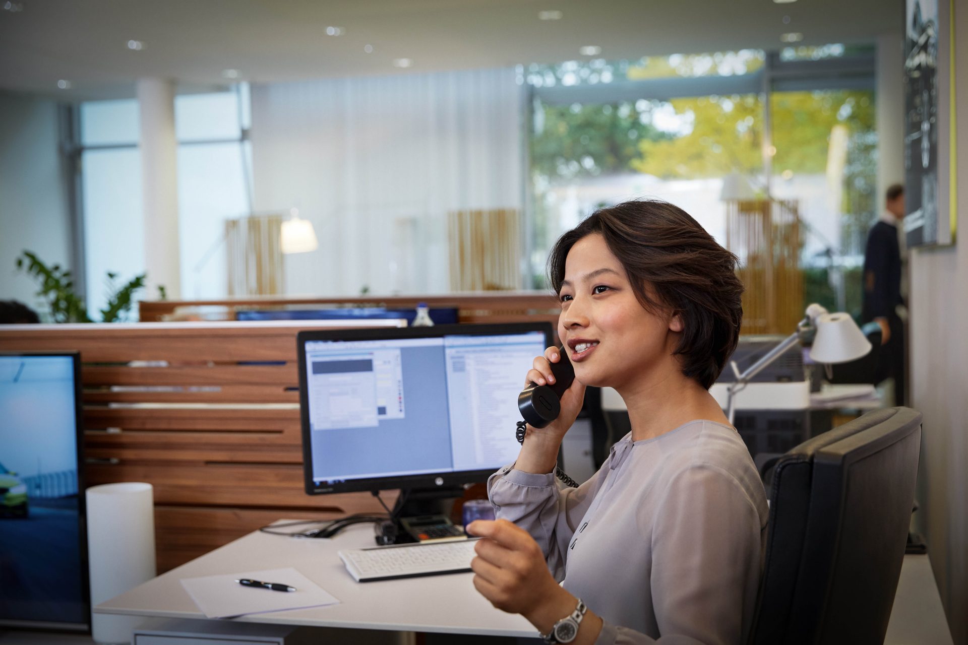 BMW employee providing customer service related to construction and services, seated at a desk.