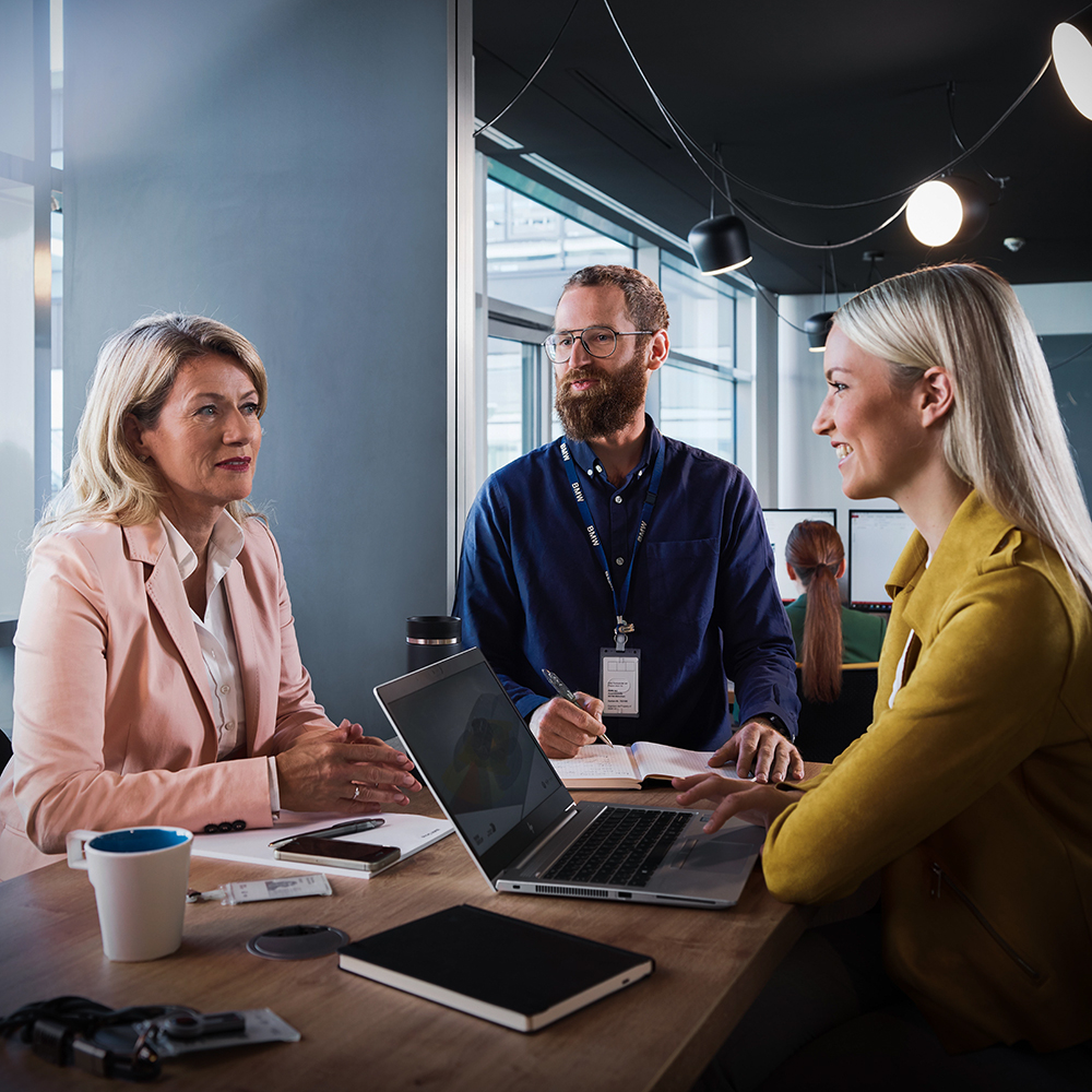 Three colleagues in a meeting room having a conversation