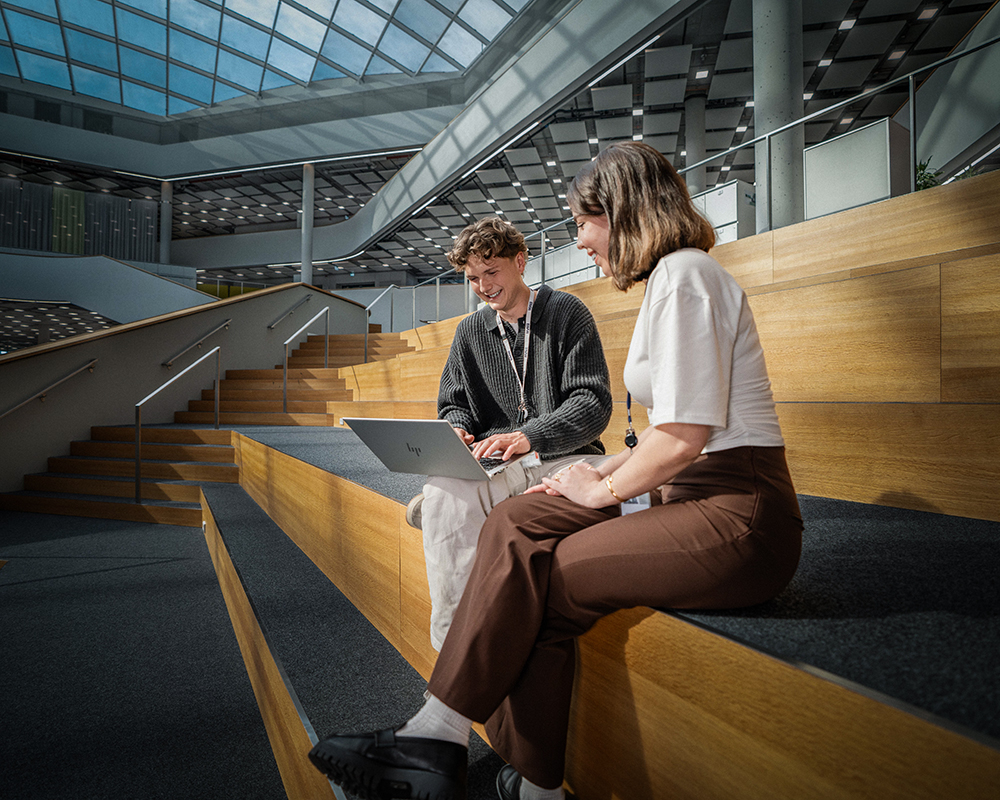 Two apprentices working with a laptop and a little robot
