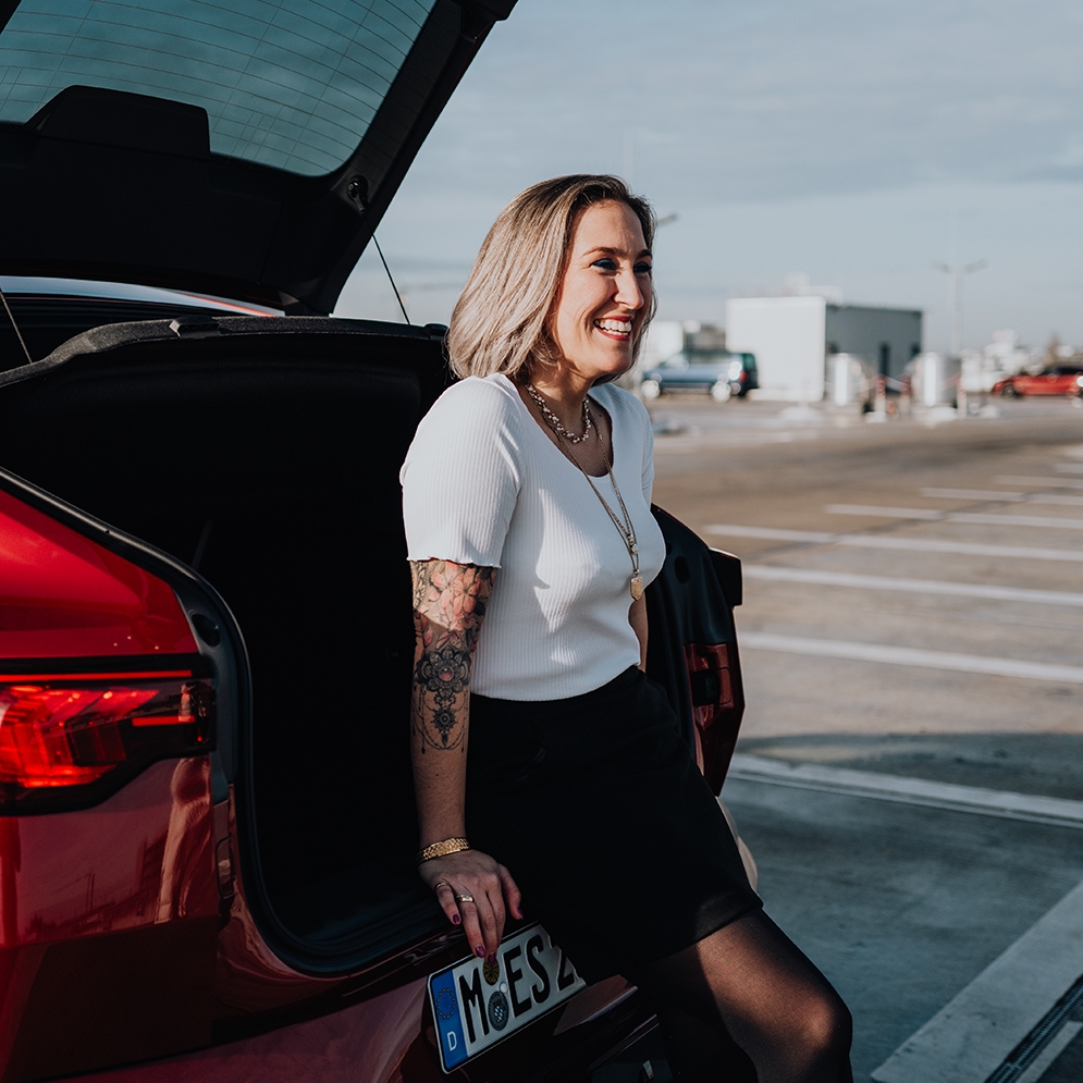 BMW employee Julia sitting at the rear of a red BMW X2