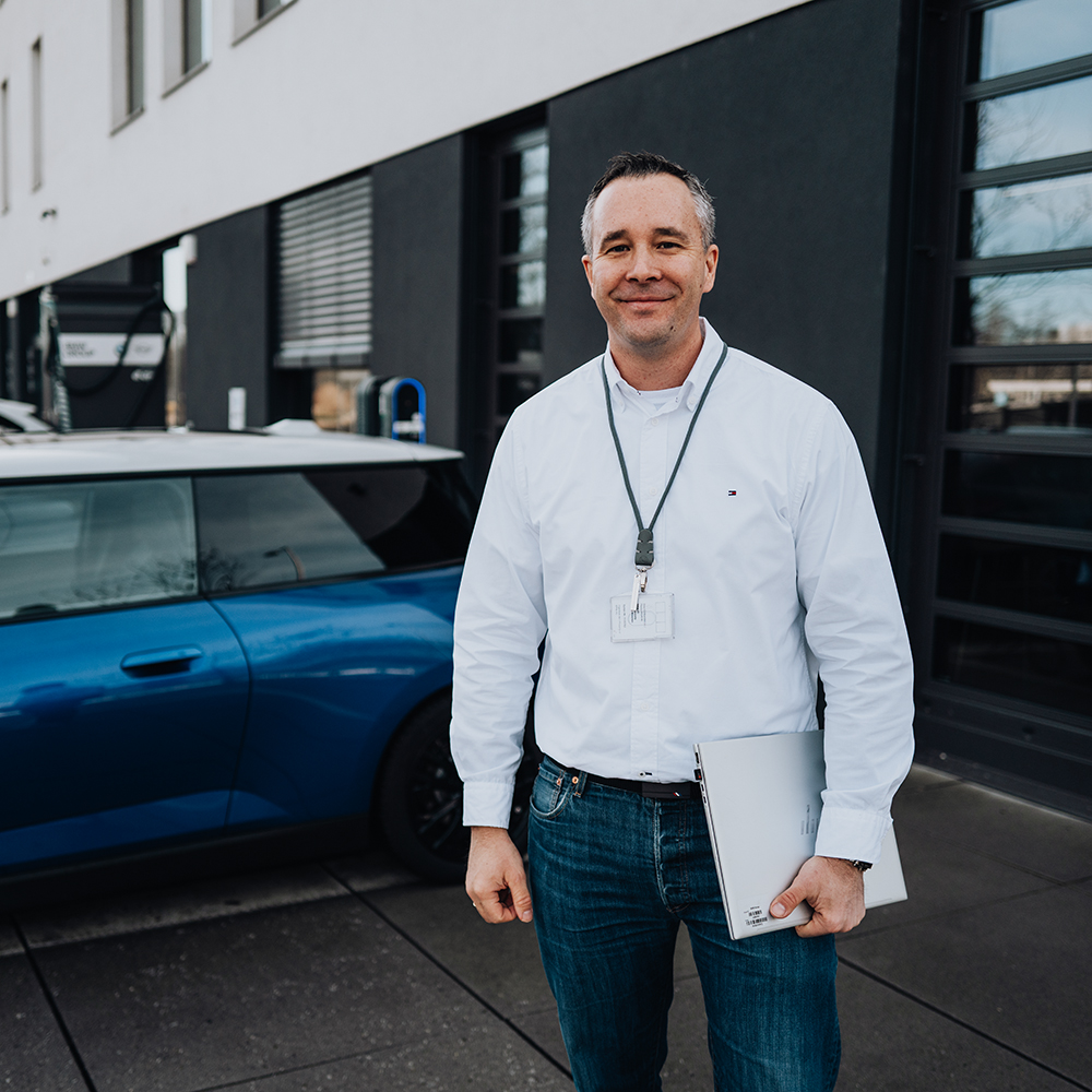 BMW employee Bastian with his laptop standing in front of BMW campus Freimann