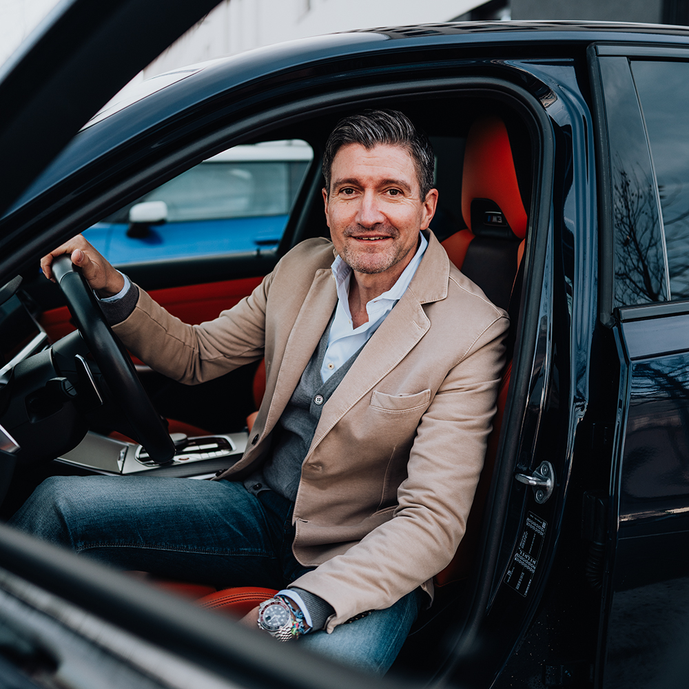 Head of Risk Management Andreas sitting in a BMW M3 and smiling