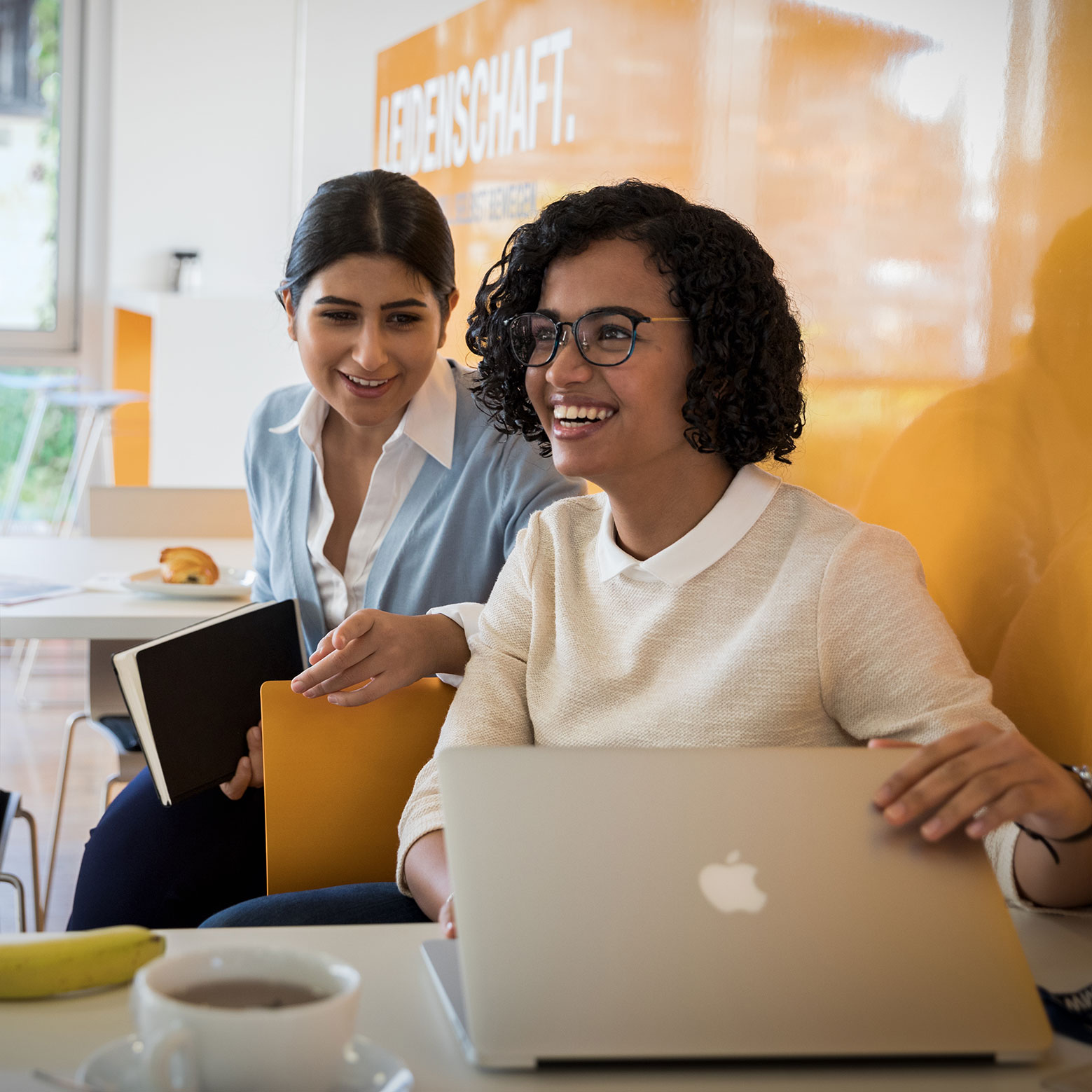 Smiling BMW employees working together on a laptop.