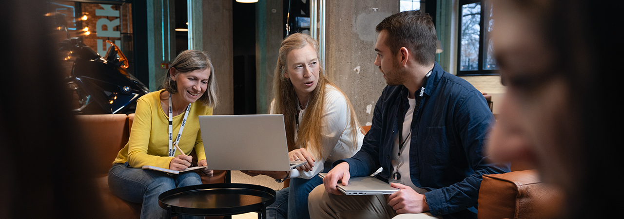 Three BMW employees in a meeting with a laptop on a sofa landscape