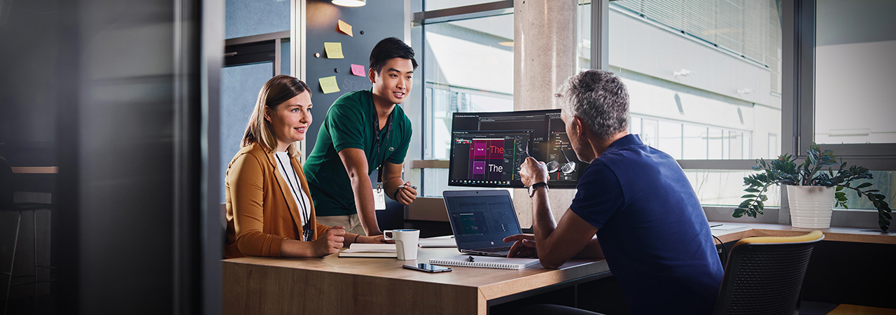 Two students talking with a colleague in a modern office environment.