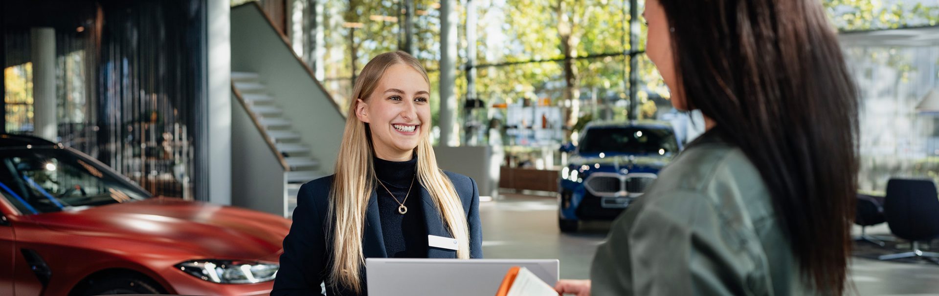 A kind salesperson in a BMW car dealership having a conversation with a customer.