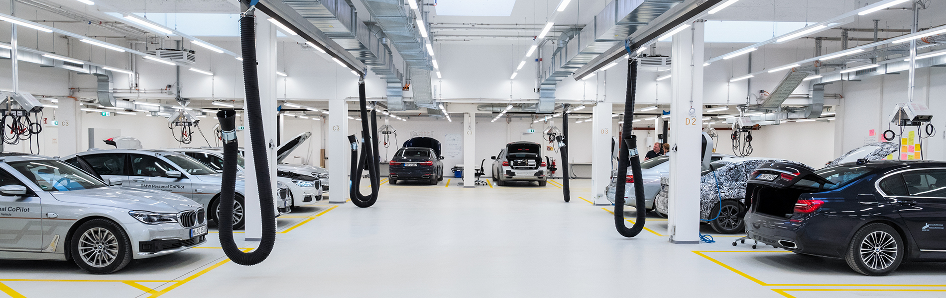 Interior shot of a BMW Group workshop with many different BMW cars inside.
