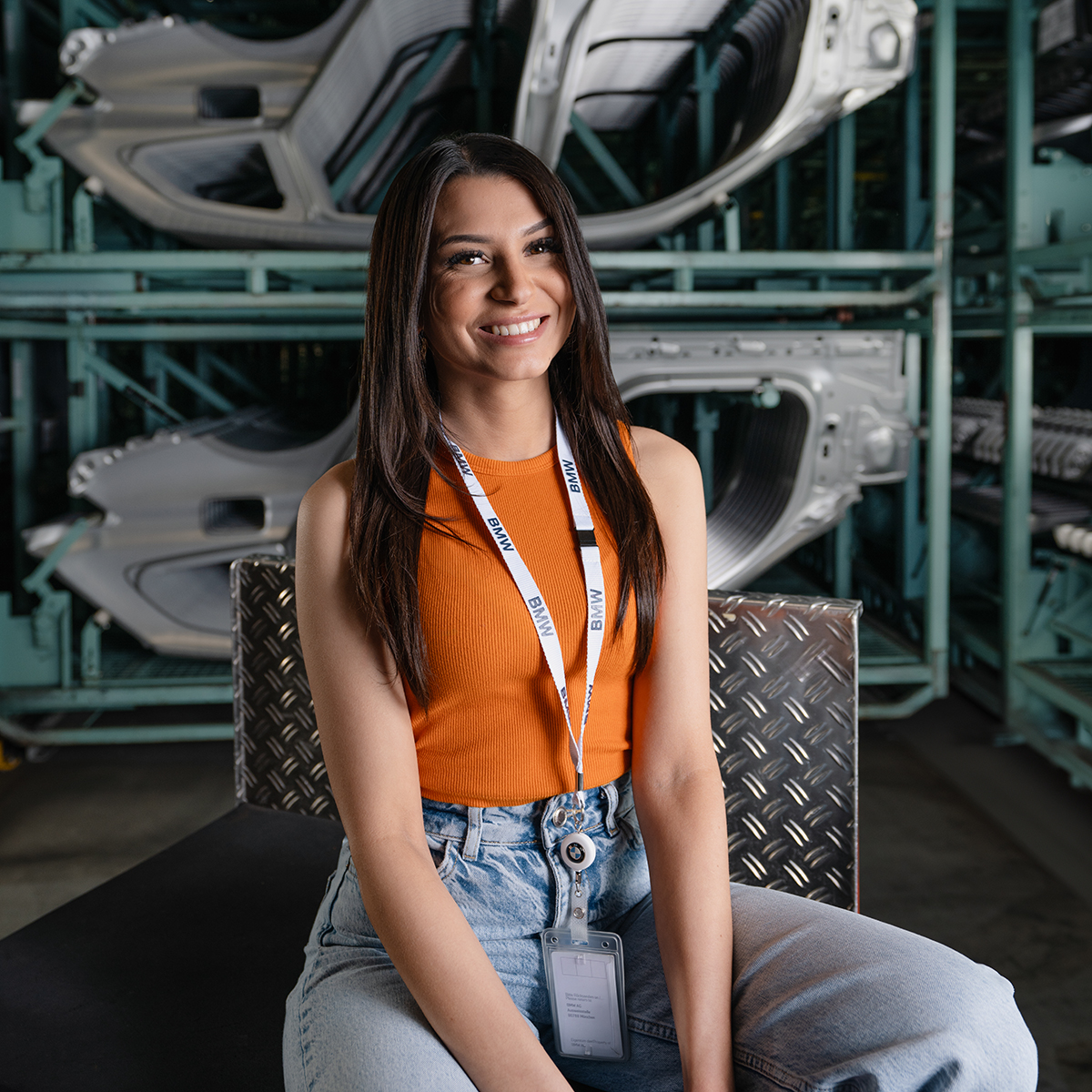 Allicia smiles in front of stored bodywork parts.