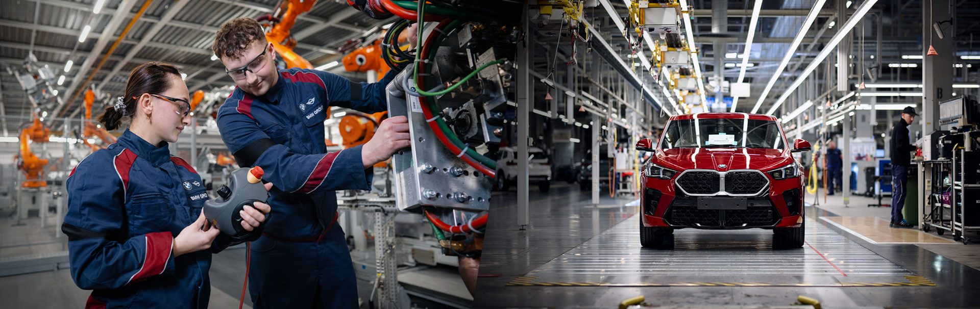 Two employees in maintenance and a red BMW X2 on the assembly line
