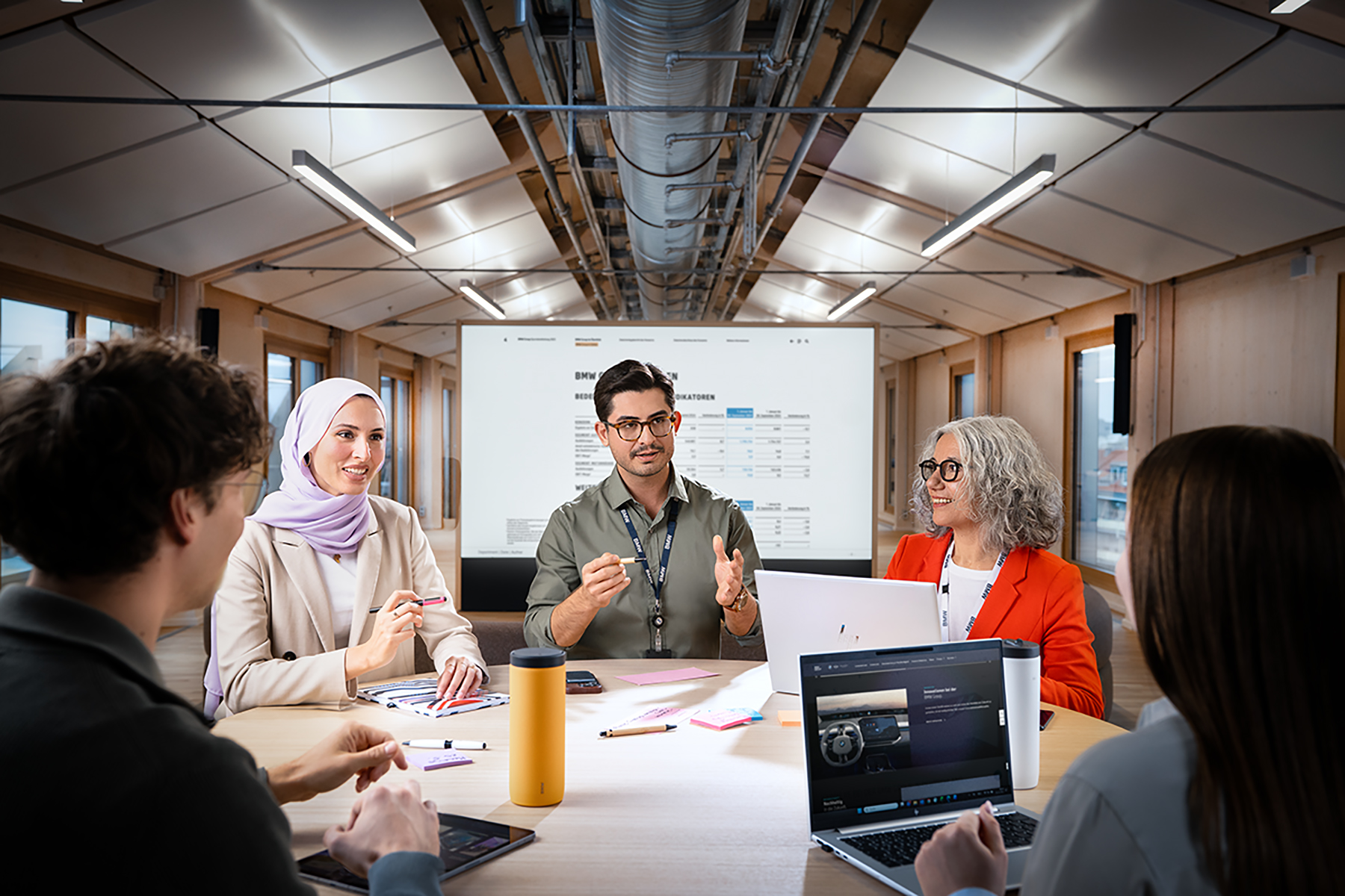 A group of colleagues in a modern workshop setting, engaged in a discussion.