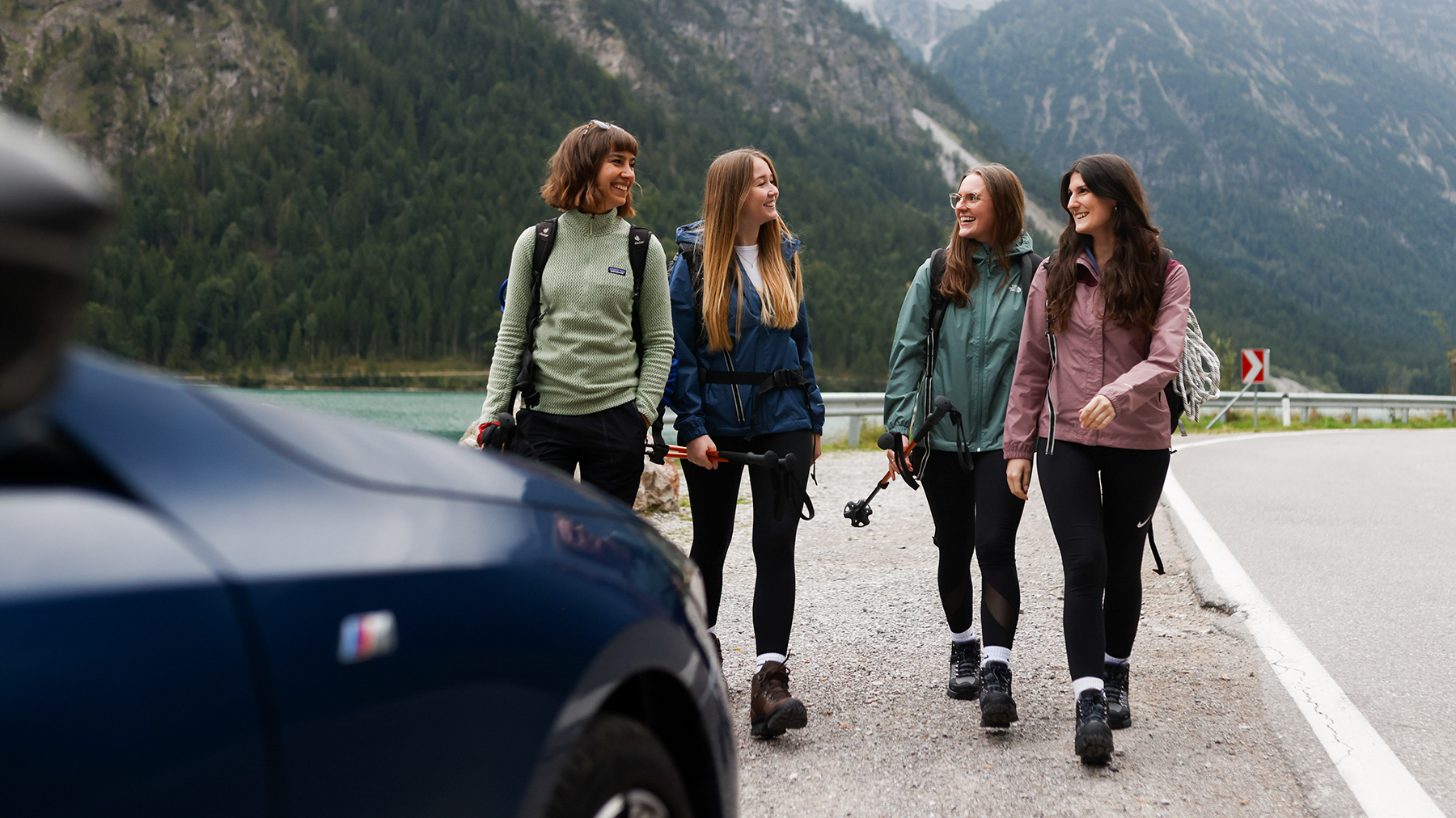 A group of employees hiking alongside a BMW vehicle.